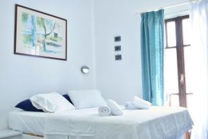 um quarto branco com 2 camas e uma janela em Martinos Studios em Kithnos