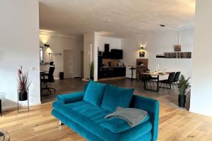 a living room with a blue couch and a dining room at cameiroo - Apartment Euskirchen in Euskirchen