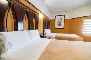 a hotel room with two beds and a window at Hotel Alcazar - Guadalajara Centro Historico in Guadalajara