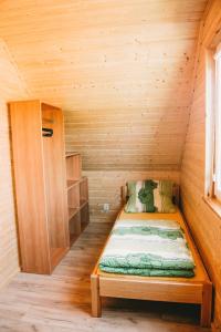 コパリノにあるDomki U Edziaの木造キャビン内のベッド1台が備わる小さな客室です。