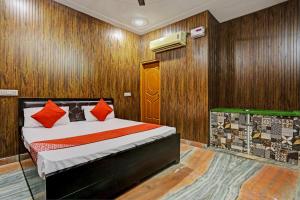 a bedroom with a bed with red pillows on it at Hotel Parvesh in Farrukhnagar