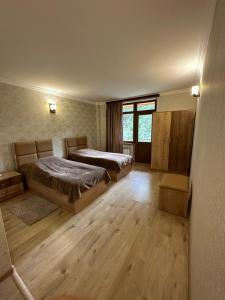 two beds in a room with wooden floors and windows at Sochiner Hotel in Vanadzor