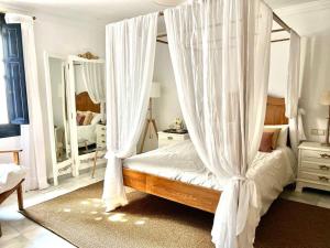 a bedroom with a canopy bed with white curtains at Villa Paula Valencia in Manises