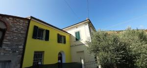 a yellow house and a white building with a fence at La casa gialla del Ristoro Agricolo Vecchiano in Vecchiano