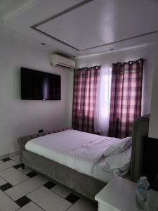 a bedroom with a bed and a tv and curtains at Rooftop Villa in Freetown