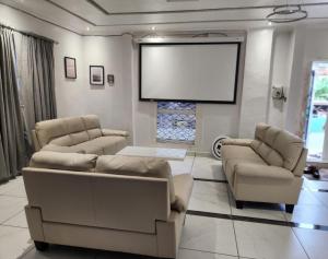 a living room with two couches and a large screen at Rooftop Villa in Freetown