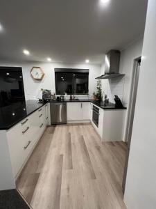 una cucina con armadietti bianchi e pavimenti in legno di Convenient and comfortable Waitara a Waitara