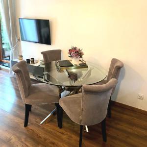 a glass dining room table with chairs and a television at SOSNOWA Apartament in Ełk