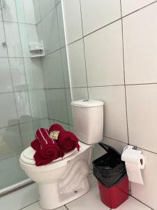 a bathroom with a toilet with red towels on it at pousada Guadalupe in Olinda