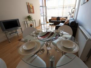 comedor con mesa de cristal y sillas en Stay Deansgate Apartments for 14 nights plus en Mánchester