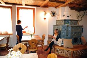a woman sitting on a couch in a living room with a fireplace at Appartamenti e Camere Veronica in Cogolo