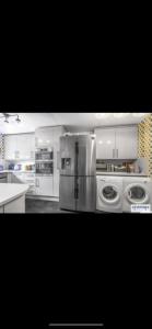 una cocina con armarios blancos y electrodomésticos de acero inoxidable en Your Perfect Place to Relax en Havering atte Bower