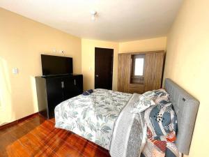 Schlafzimmer mit einem Bett und einem Flachbild-TV in der Unterkunft Departamento independiente in Atuntaqui