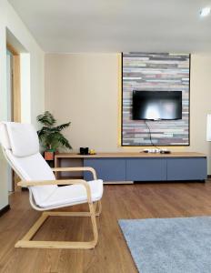 een woonkamer met een witte stoel en een tv bij NIKAS Apartman in Donji Milanovac