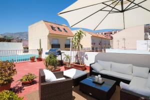 a patio with a couch and an umbrella at Andalucian house, few minutes from the beach in Fuengirola