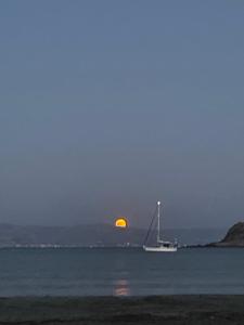 ein Segelboot im Wasser mit dem Mond im Hintergrund in der Unterkunft Molos Sea View House - Paros Greece in Molos Parou