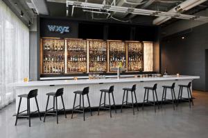 a bar with stools in a room with wine bottles at Aloft Kansas City Country Club Plaza in Kansas City