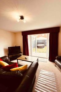 a living room with a leather couch and a sliding glass door at 5 STAR LUXURY BIG HOUSE, JACUZZI SPA HOT TUB, PARKING, LIVERPOOL CITY CENTRE, SLEEPS 10, EASY LOCK BoX ENTRY! NO PARTIES! in Liverpool