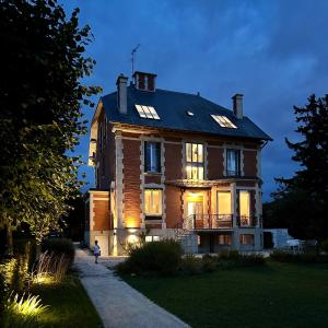 a large brick house with lights on at LA GRANDE MAISON LGM in Lesches