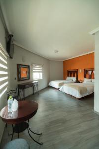 グアダラハラにあるHotel Alcazar - Guadalajara Centro Historicoのベッド2台とテーブルが備わるホテルルームです。
