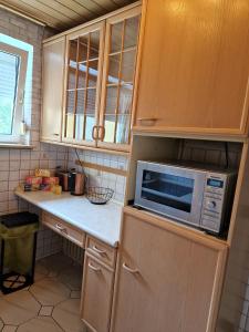 eine Küche mit Holzschränken und einer Mikrowelle in der Unterkunft Maria Apartment in Wolfsburg