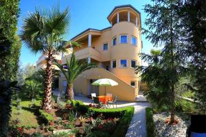a large yellow building with palm trees in front of it at Villa Jelena in Zadar