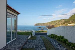 a walkway next to a house with a view of the ocean at Serenity Villa - Azorean Butler in Mosteiros