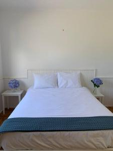 a bed with white sheets and pillows on it at Serenity Villa - Azorean Butler in Mosteiros
