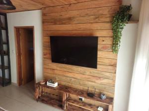 sala de estar con pared de madera y TV de pantalla plana en Casas Bueno en Camanducaia