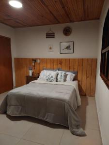 1 dormitorio con 1 cama grande y pared de madera en Casas Bueno en Camanducaia