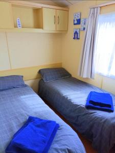2 camas en una habitación con sábanas azules y ventana en Snowdon Retreat, en Llanrug