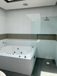 Baño blanco con bañera y pared de cristal en Casa helenico, en Ciudad de México