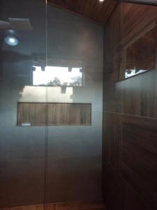 y baño con ducha acristalada y ventana. en Casas Bueno en Camanducaia
