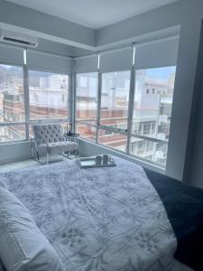 sypialnia z łóżkiem, krzesłem i oknami w obiekcie The7penthouse w mieście Santa Cruz de Tenerife