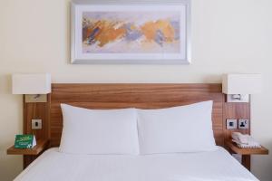 a bedroom with a white bed with two lights above it at Holiday Inn Haydock by IHG in Haydock