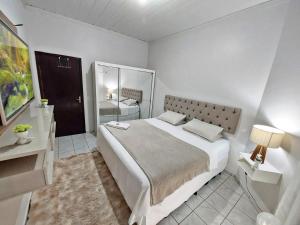 a white bedroom with a large bed and a bathroom at Hospedagem Domiciliar em Lucas do Rio Verde in Lucas do Rio Verde