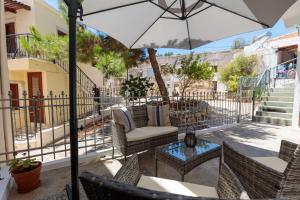 een patio met een tafel en stoelen en een parasol bij Bluebell House Halki in Halki