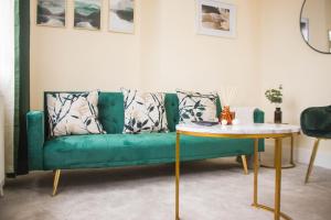 3 beds - Spacious garden في Streatham Vale: أريكة خضراء في غرفة المعيشة مع طاولة