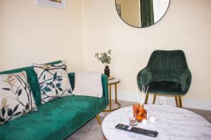 3 beds - Spacious garden في Streatham Vale: غرفة معيشة مع أريكة خضراء وطاولة