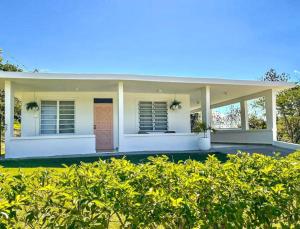 a white house with a brown door and some bushes at Casa Eve near Gozalandia Waterfalls in San Sebastian