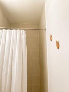 a shower with a white shower curtain in a bathroom at Casa Eve near Gozalandia Waterfalls in San Sebastian