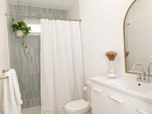 a white bathroom with a shower curtain and a toilet at Casa Eve near Gozalandia Waterfalls in San Sebastian