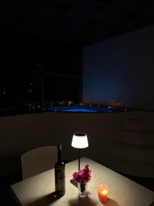 a bottle of wine and flowers on a table with a lamp at Tristhenia in Perissa