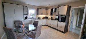 a kitchen with a table and chairs and a kitchen with white cabinets at The Quays Apartment in Annalong