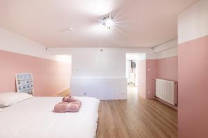 Un dormitorio con una cama blanca y una luz en el techo en La vie en rose - appartement cosy - centre ville, en Auch