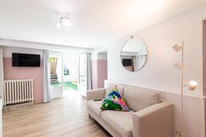 een woonkamer met een bank en een spiegel bij La vie en rose - appartement cosy - centre ville in Auch
