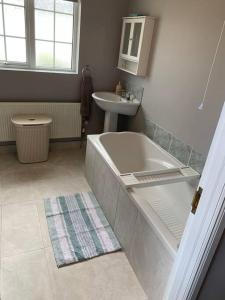 een badkamer met een bad en een wastafel bij Gortamaddy House in Ballycastle