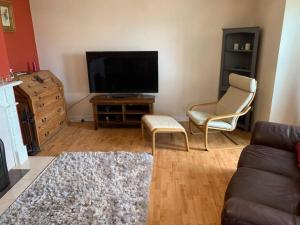 een woonkamer met een bank en een flatscreen-tv bij Gortamaddy House in Ballycastle