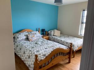 een slaapkamer met 2 bedden en een blauwe muur bij Gortamaddy House in Ballycastle