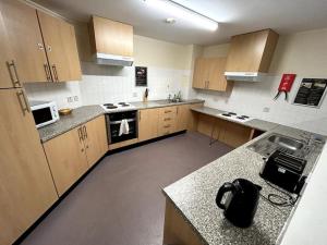 a large kitchen with wooden cabinets and appliances at Spacious Ensuite Room With Shared Kitchen and Living Room in Crewe